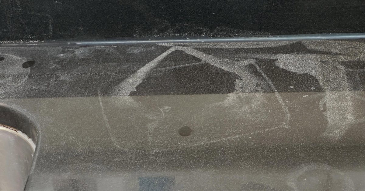 Dark speckled granite worktop with marks before restoration