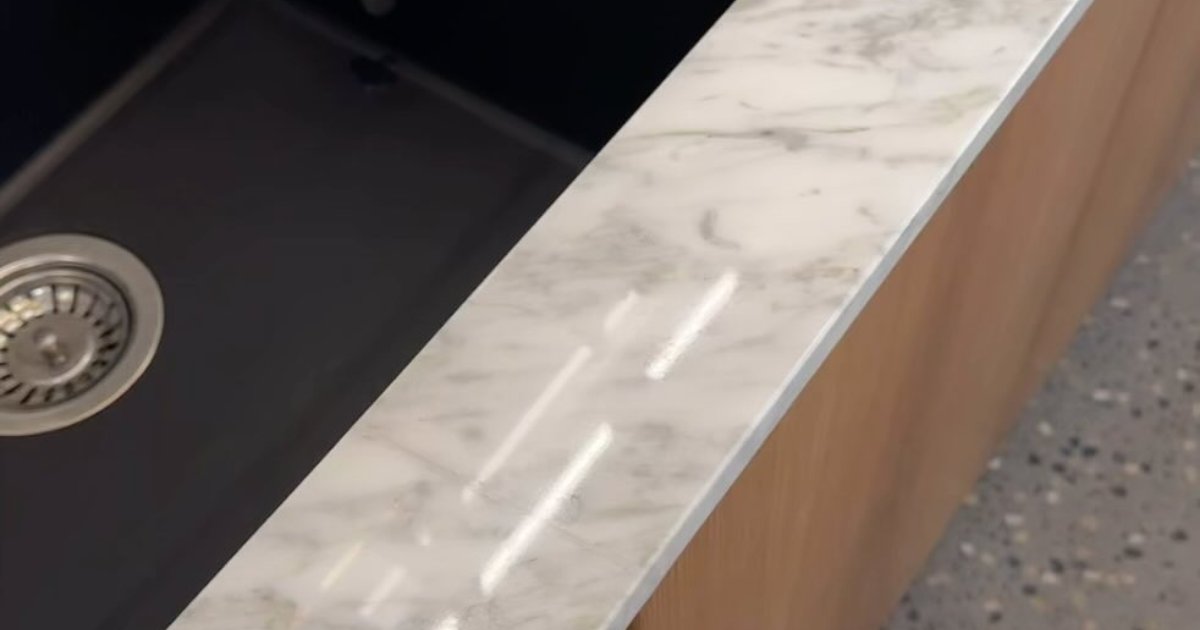 White marble worktop edge around a black undermount sink