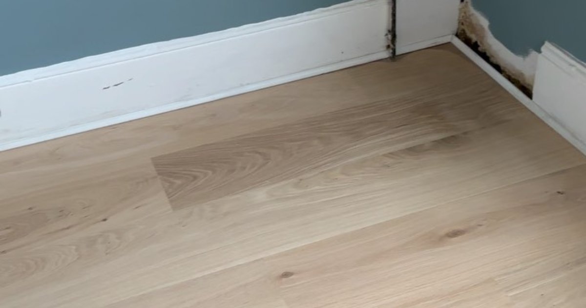 Light oak wooden floor next to a white skirting board