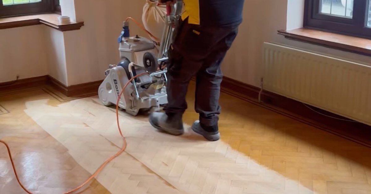Technician sanding a herringbone parquet floor with a floor sanding machine