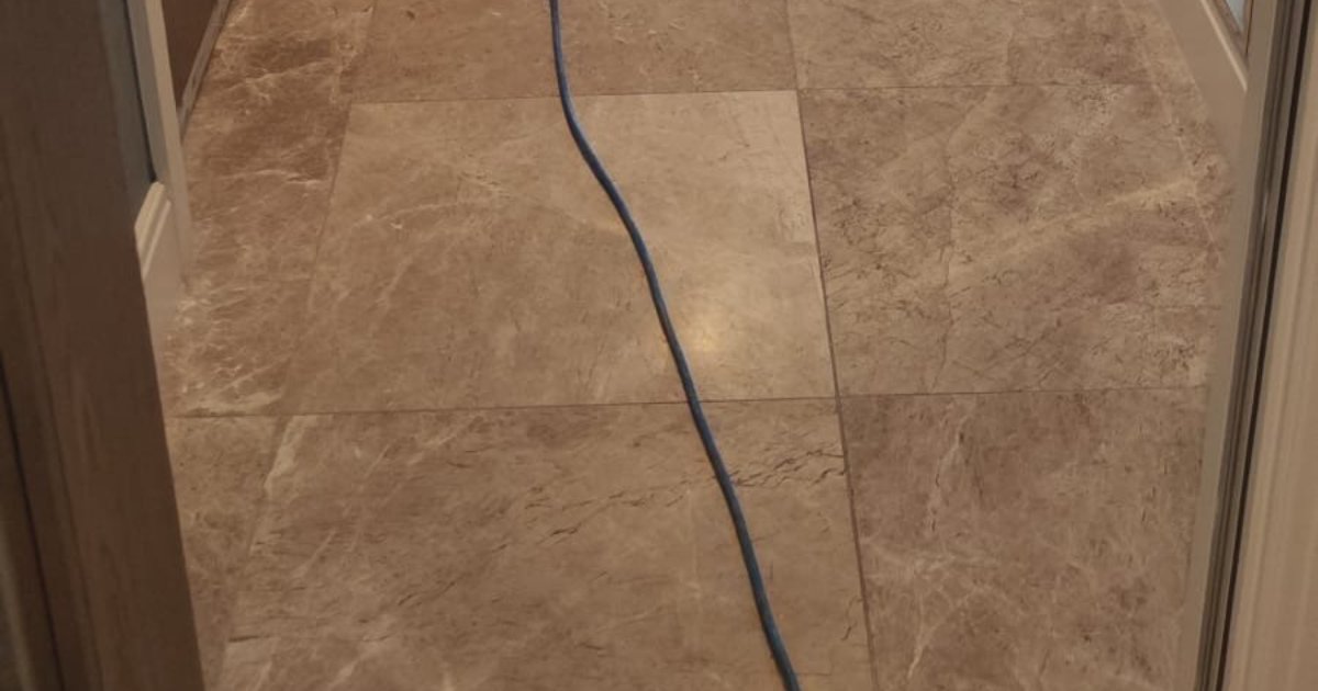 Polished beige stone floor tiles in a hallway during machine cleaning