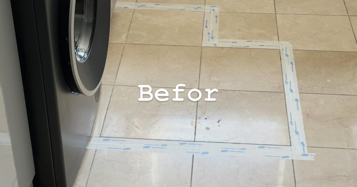 Light floor tiles beside a washing machine with a cleaned test section of grout